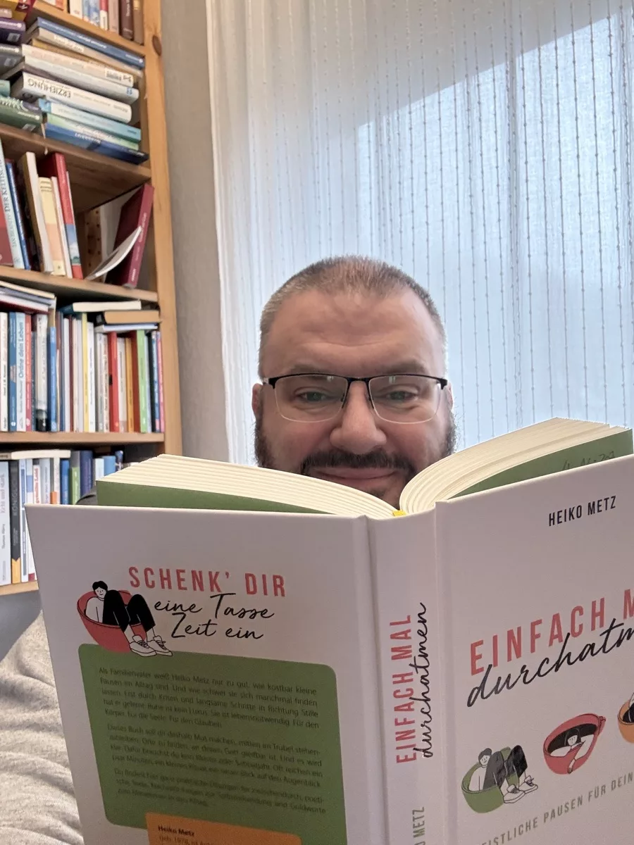 Heiko Metz hinter seinem Buch Einfach mal durchatmen, im Hintergrund sein Bücherregal