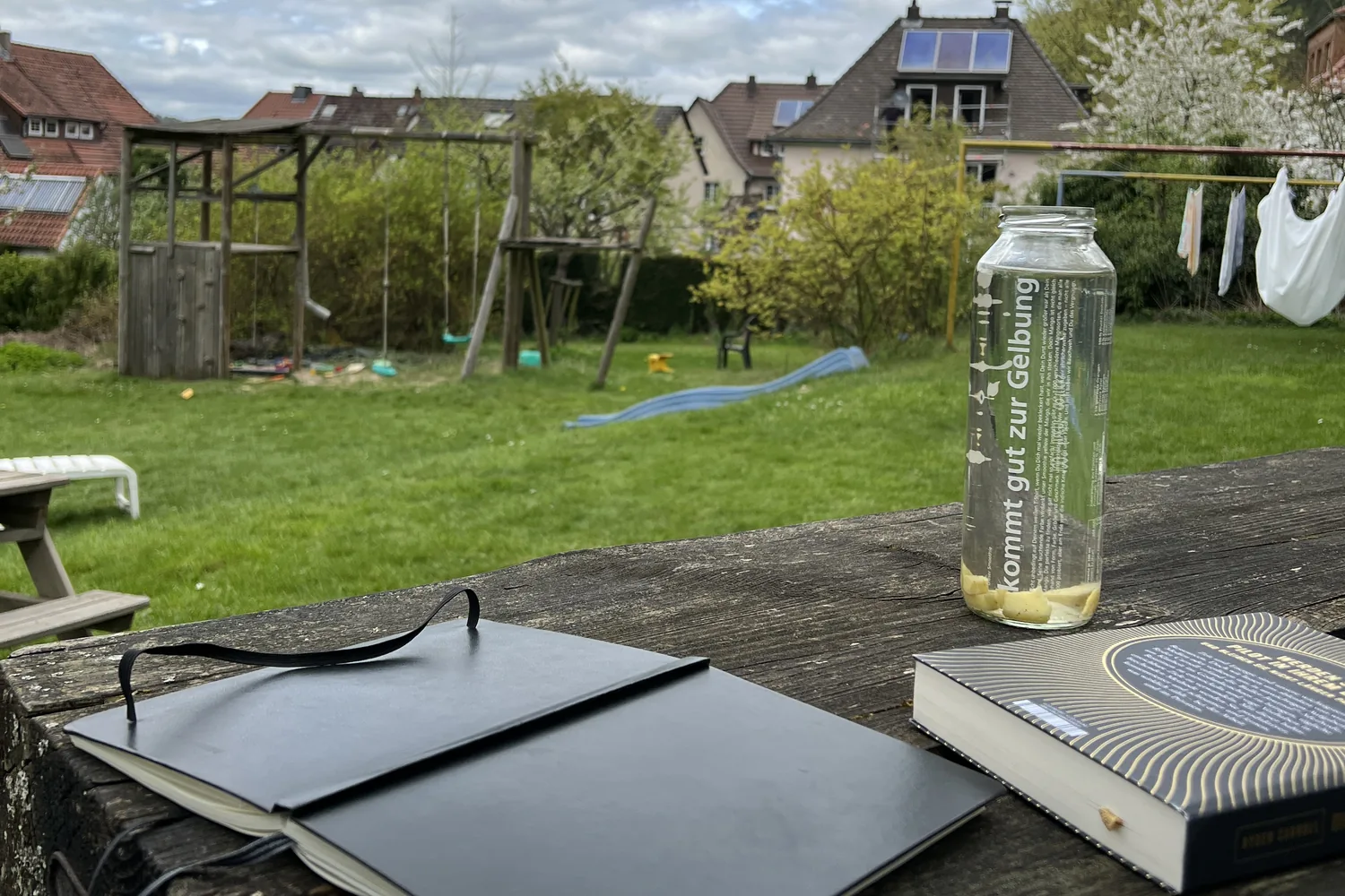 Notizbuch und Wasserflasche auf einem Gartentisch - Heiko Metz