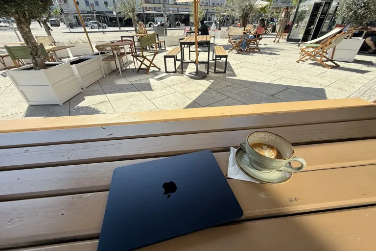 Zugeklappter Laptop und eine Tasse Kaffee auf einer Holzbank - Heiko Metz