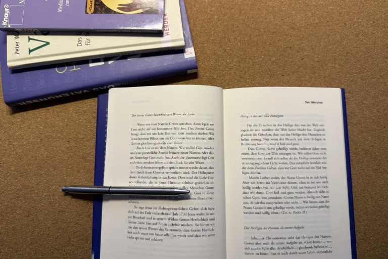 Aufgeschlagenes Buch mit Stift auf dem Tisch, daneben weitere Bücher - Heiko Metz