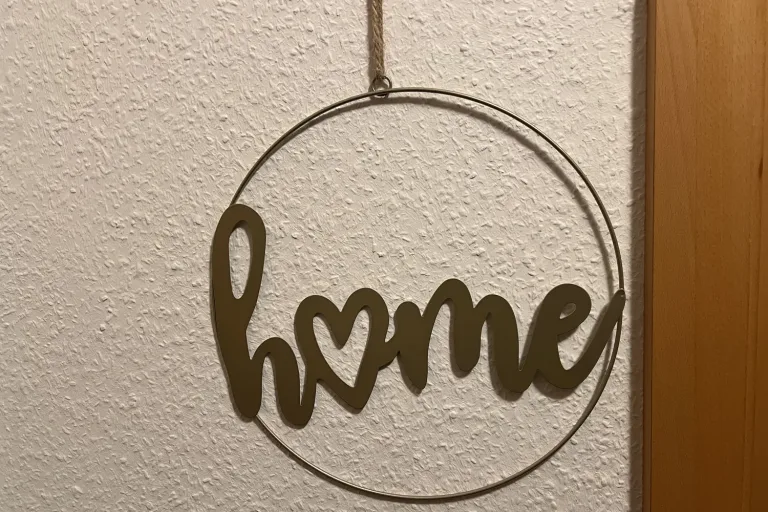 Metallring mit dem Wort home an der Wand neben der Tür - Heiko Metz