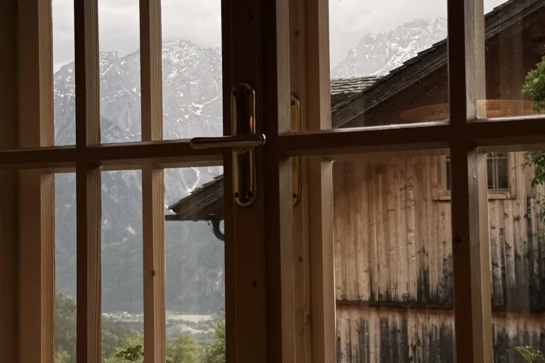 Blick durch ein Sprossenfenster auf Berge im Nebel - Heiko Metz