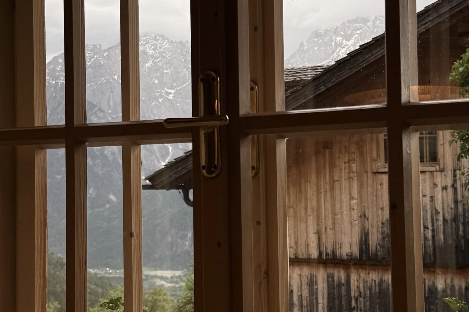 Blick durch ein Sprossenfenster auf Berge im Nebel - Heiko Metz
