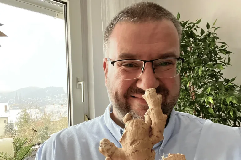 Heiko mit einer großen Ingwerknolle am Bürofenster - Heiko Metz