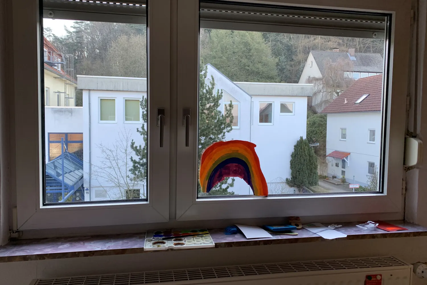 Fenster mit einem gemalten Regenbogen, Blick auf Nachbarhäuser - Heiko Metz