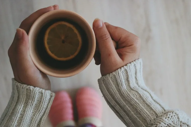 Hände halten eine Tasse Tee mit Zitrone