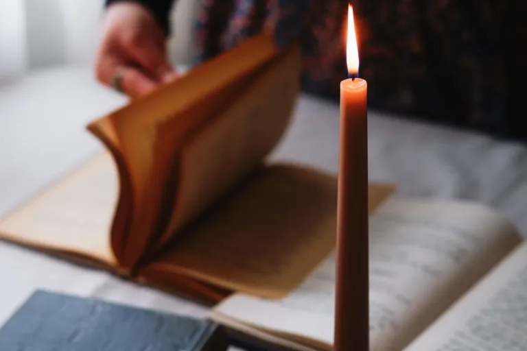 Brennende Kerze neben einem aufgeschlagenen alten Buch