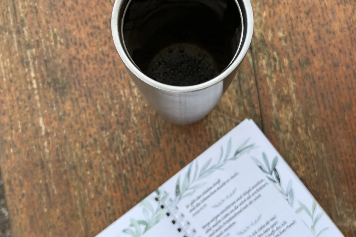 Becher Kaffee und ein Andachtsheft auf dem Holztisch - Heiko Metz