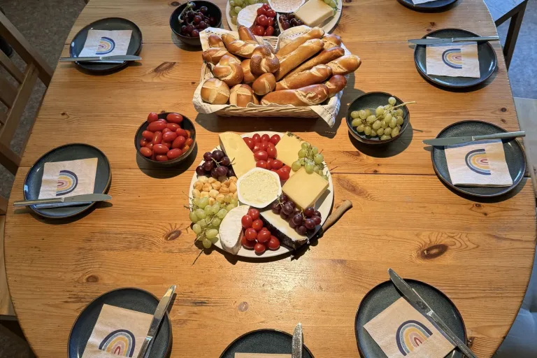 Gedeckter Tisch mit Brötchen, Käse und Obst von oben - Heiko Metz