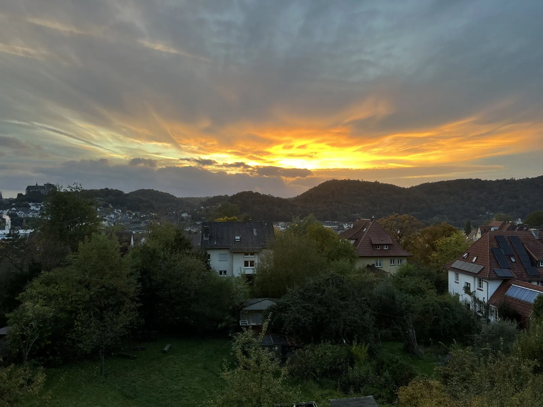 Sonnenuntergang mit leuchtend orangem Himmel über den Dächern einer Stadt - Heiko Metz