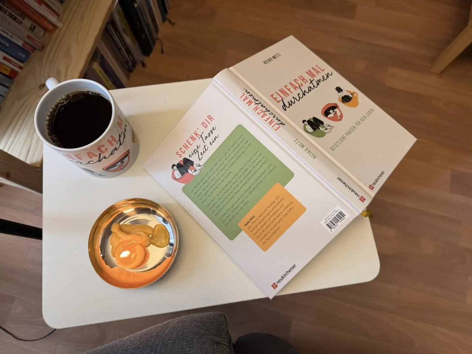 Das Buch Einfach mal durchatmen auf einem weißen Tisch neben Kaffeetasse und Teelicht - Heiko Metz