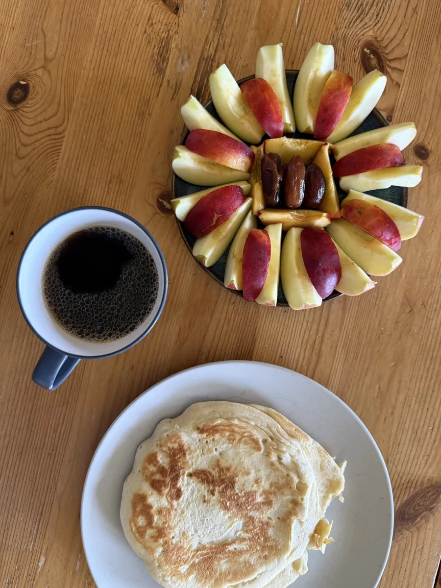 Eine Tasse Kaffee, Apfelspalten mit Datteln und ein Pfannkuchen auf einem Holztisch - Heiko Metz