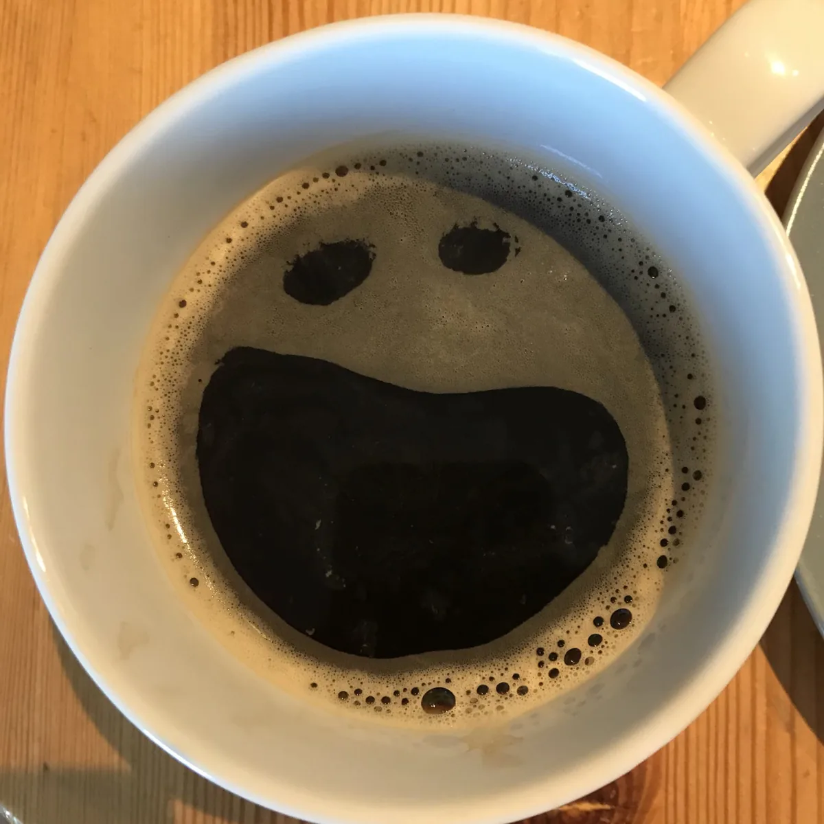 Eine Tasse schwarzer Kaffee, in der der Schaum wie ein gähnendes Gesicht aussieht - Heiko Metz