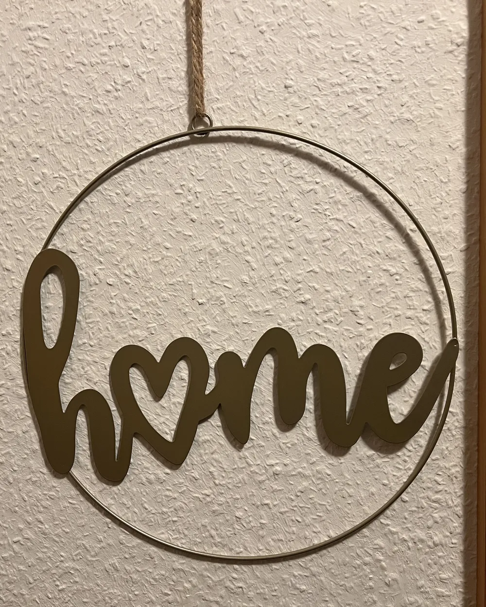 Metallring mit dem Wort home an der Wand neben der Haustür - Heiko Metz