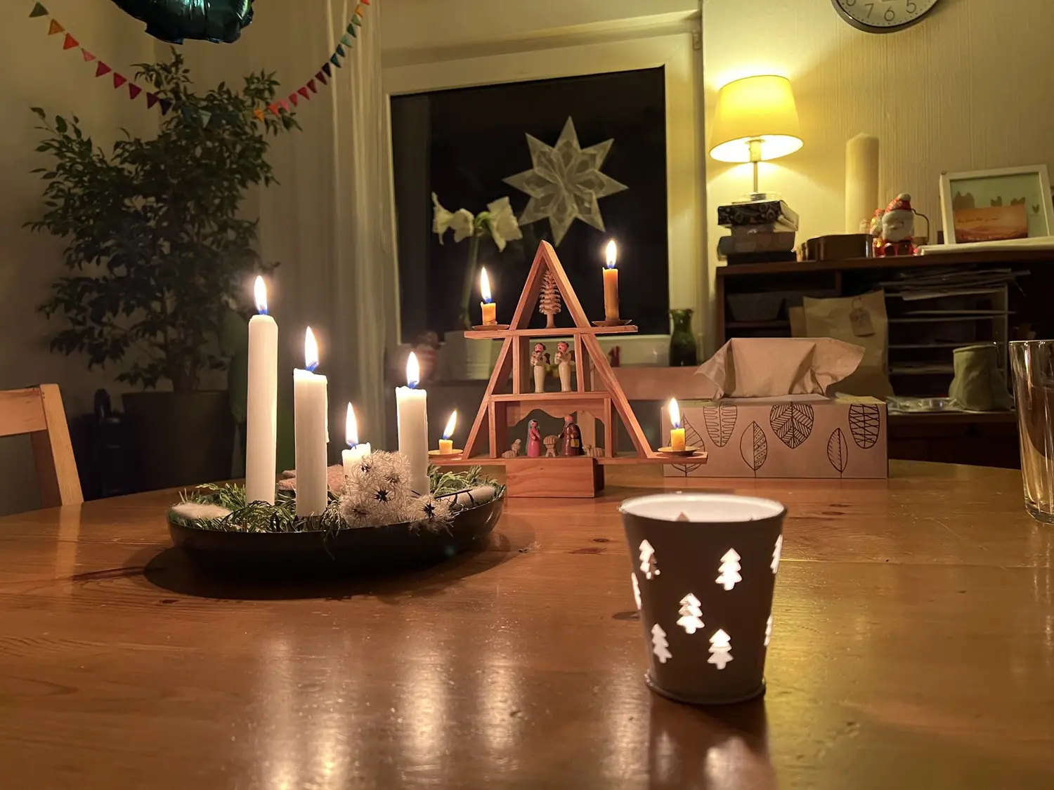 Adventskranz mit brennenden Kerzen, Pyramide und Teelicht auf einem Holztisch - Heiko Metz